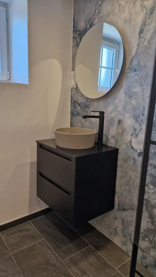 Meuble vasque, robinetterie et miroir rond dans une salle de bains