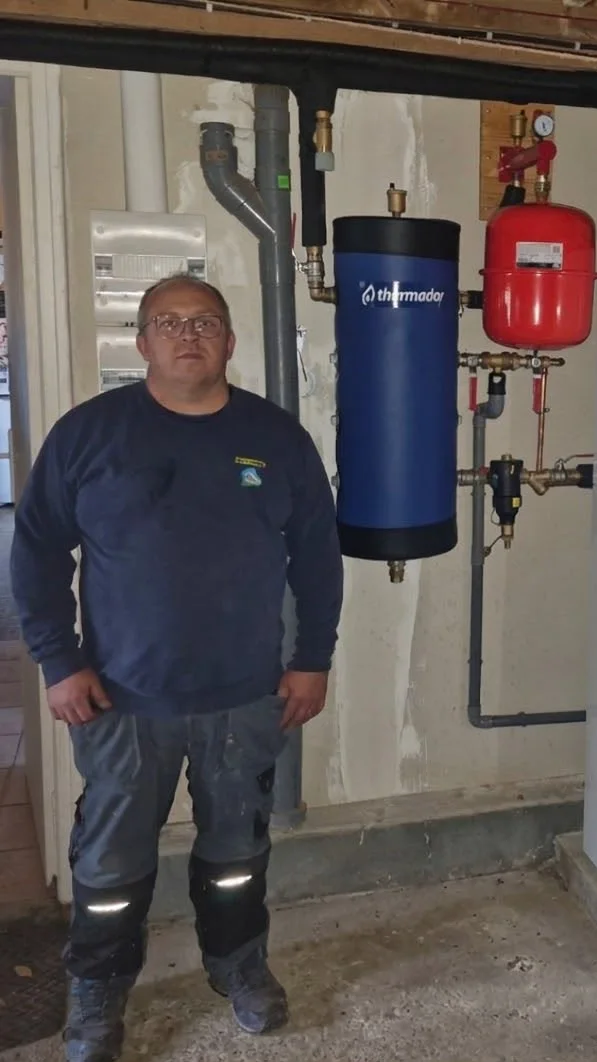 Sébastien Mauger devant une installation de chauffage avec ballon et vase d’expansion